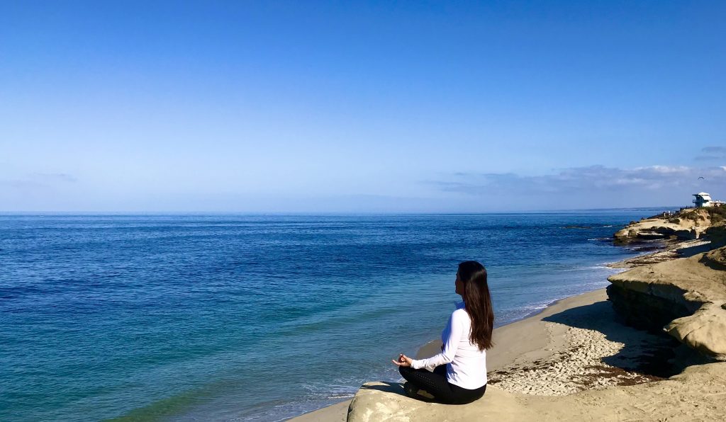 A scenic coastal road winding along rocky cliffs with a stunning ocean view under a partly cloudy sky.